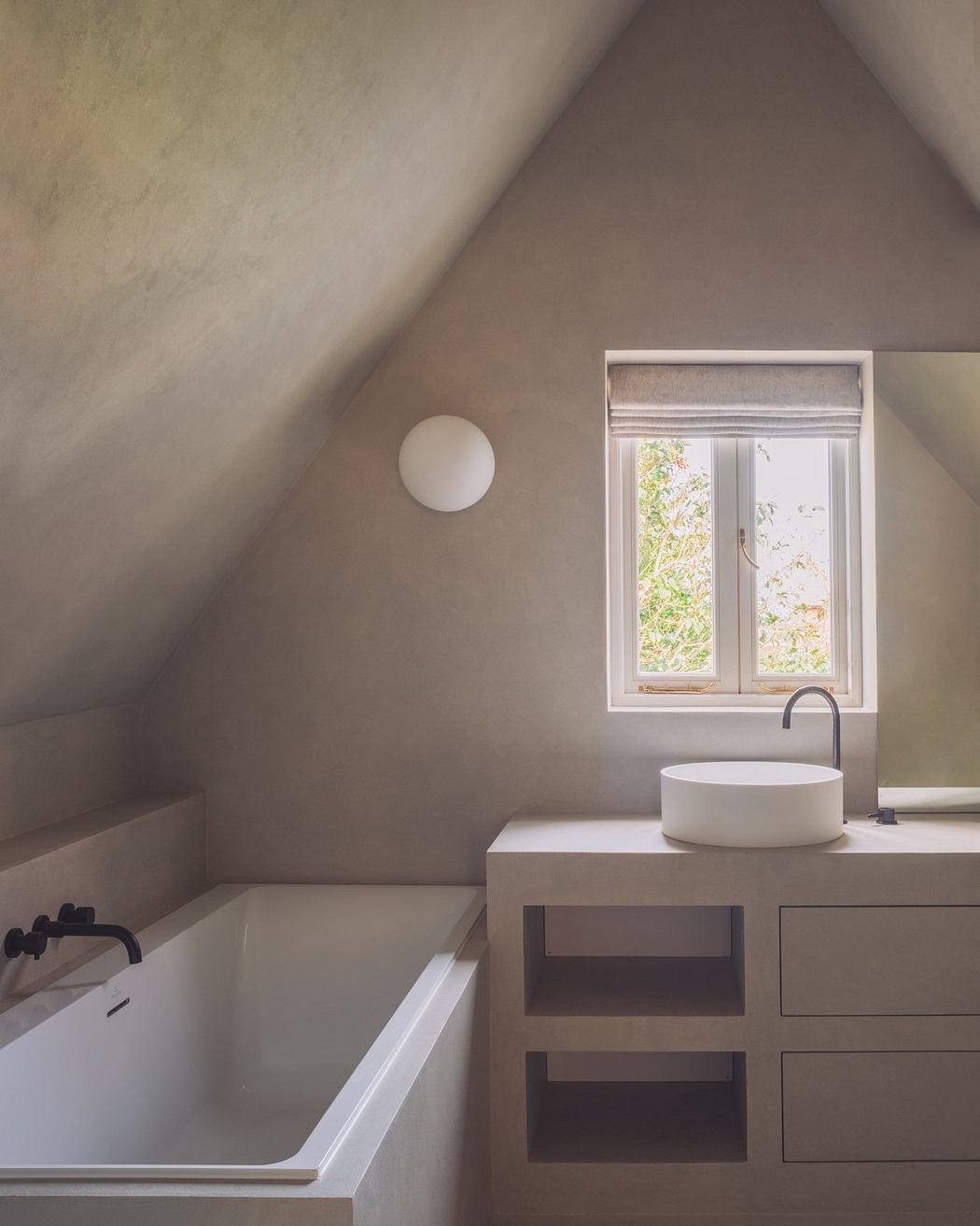 A modern bathroom with a minimalist vanity, round sink, and a large window overlooking greenery.