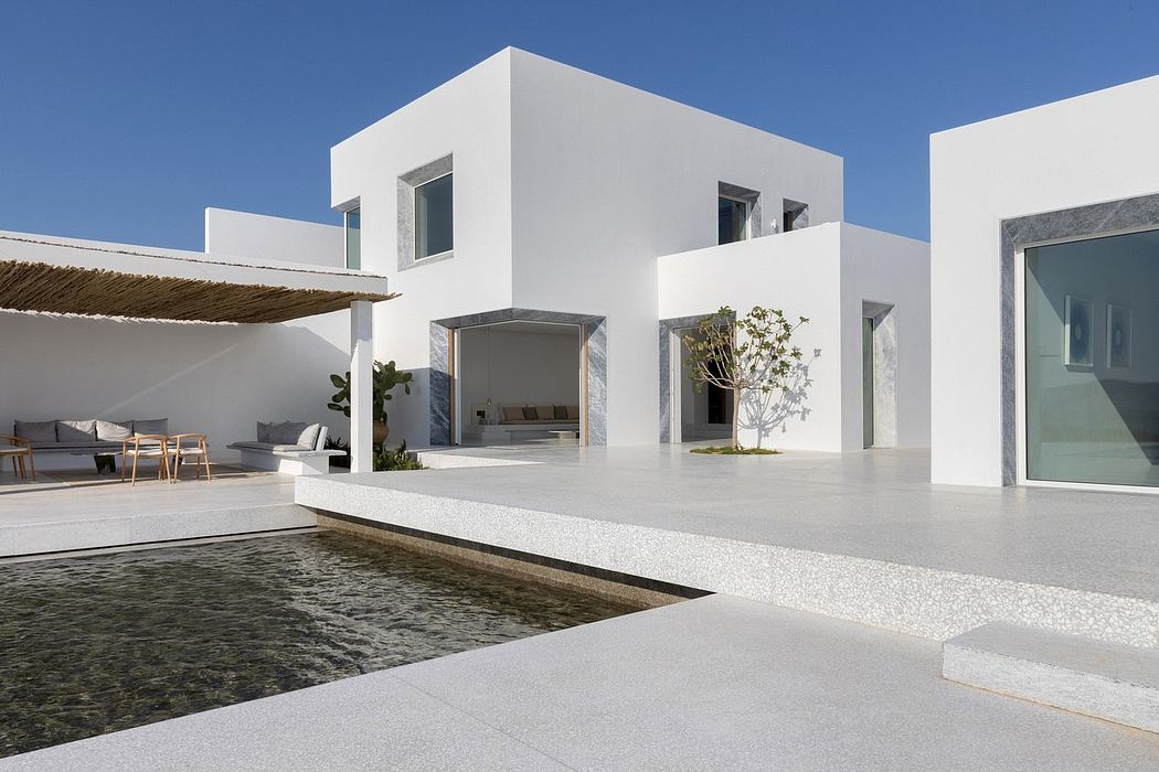Minimalist modern villa with clean white facade, pool, and terrace seating.
