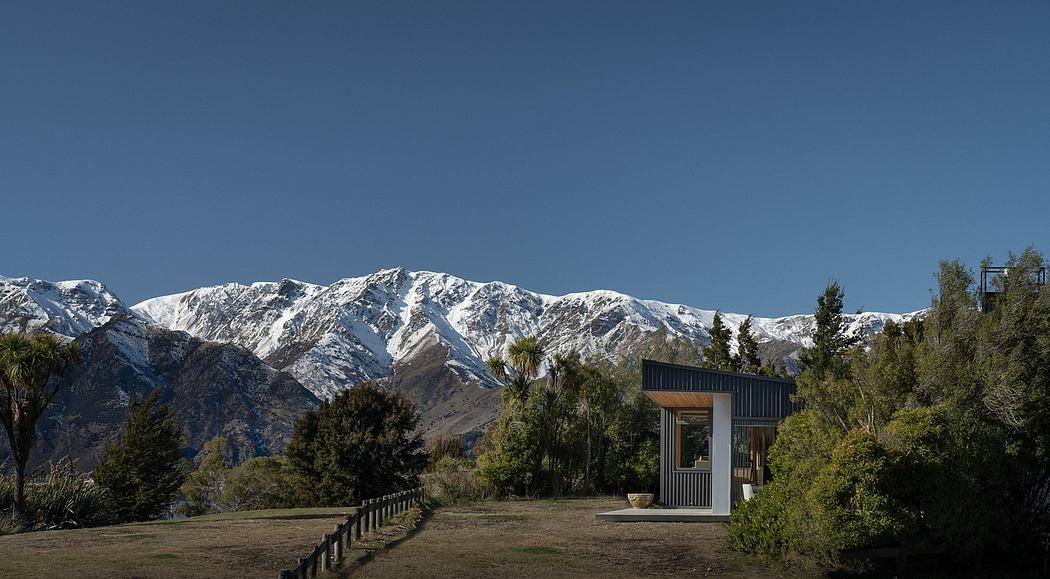 A modern pavilion structure set against a backdrop of snow-capped mountains.