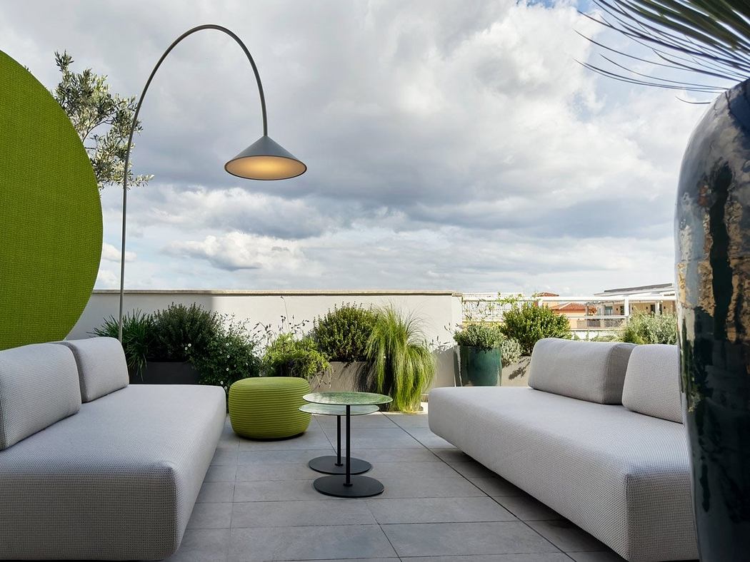 Sleek, modern outdoor seating area with curved lighting fixture, potted plants, and neutral tones.