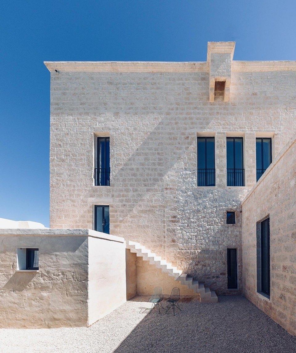 Imposing stone façade with recessed windows and stairs, creating a dramatic architectural composition.