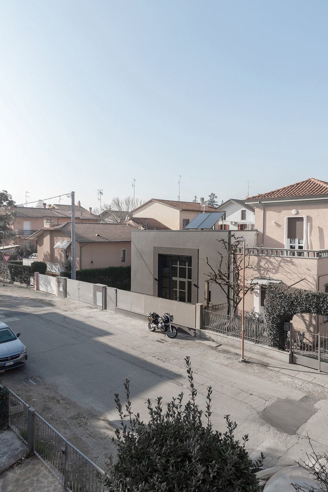 Residential neighborhood with Mediterranean architectural style, including tiled roofs and a motorcycle parked on the street.