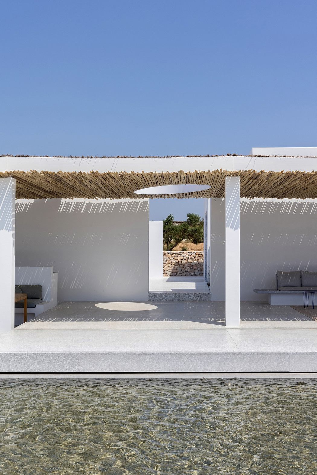 Modern architecture with a thatched roof, open-air courtyard, and tranquil pool.