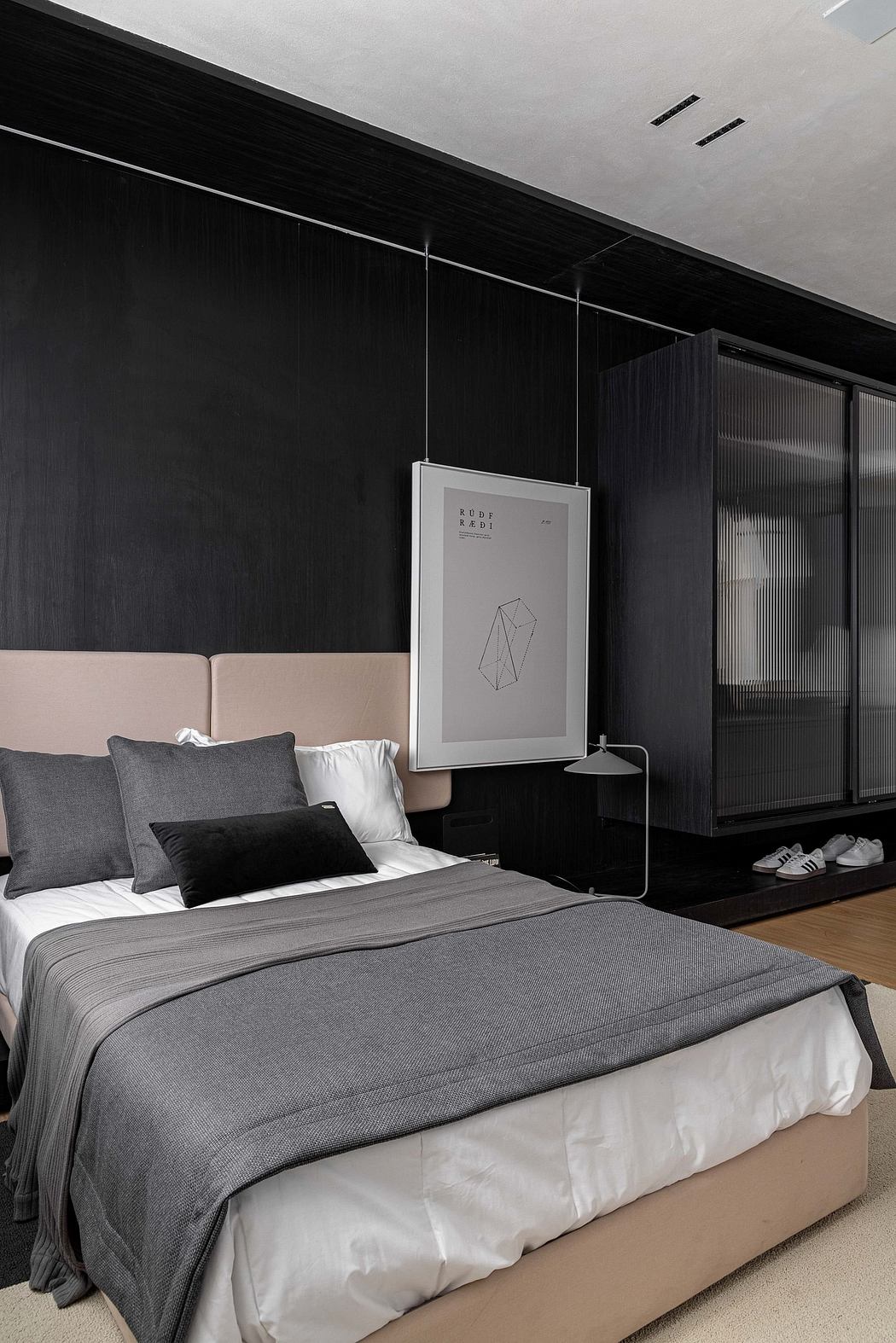 Sleek, minimalist bedroom with black walls, gray bedding, and framed geometric artwork.
