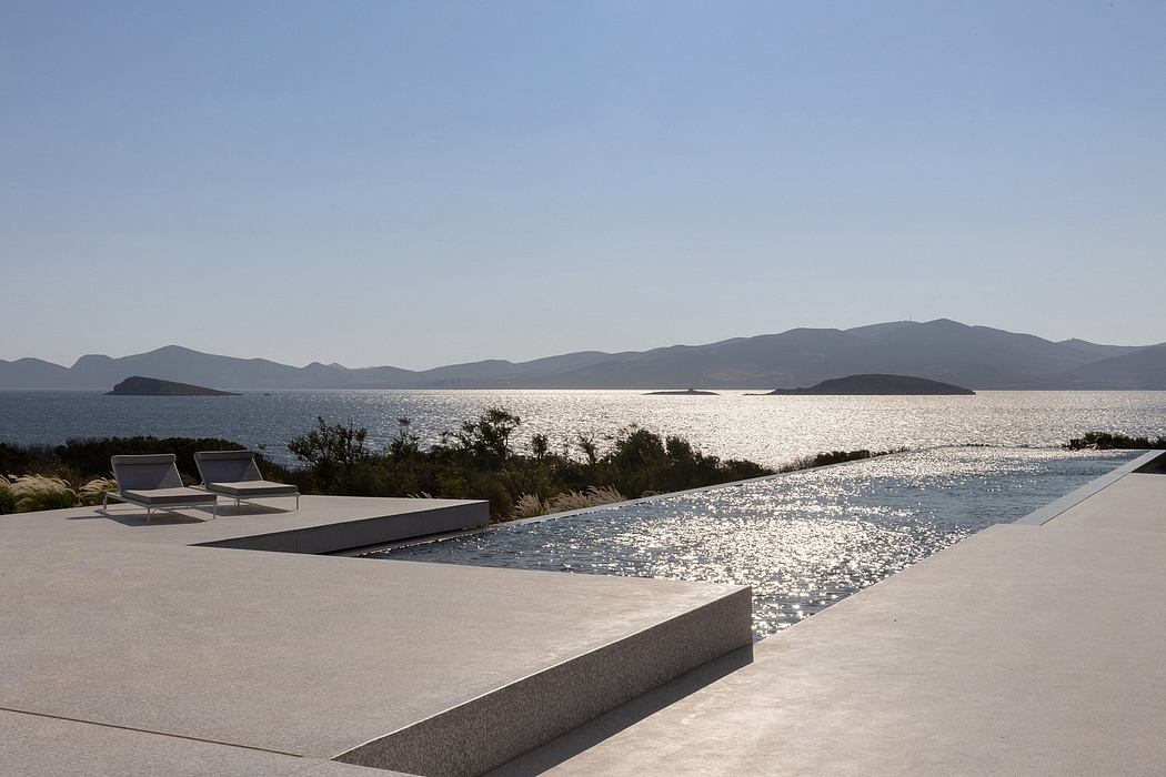 A sleek poolside lounge area with mountain and sea views in the distance.