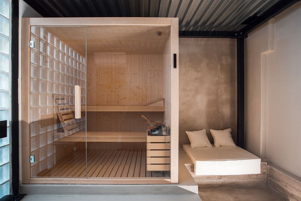 A modern, minimalist sauna with sleek wood paneling, shelves, and a cozy seating area.