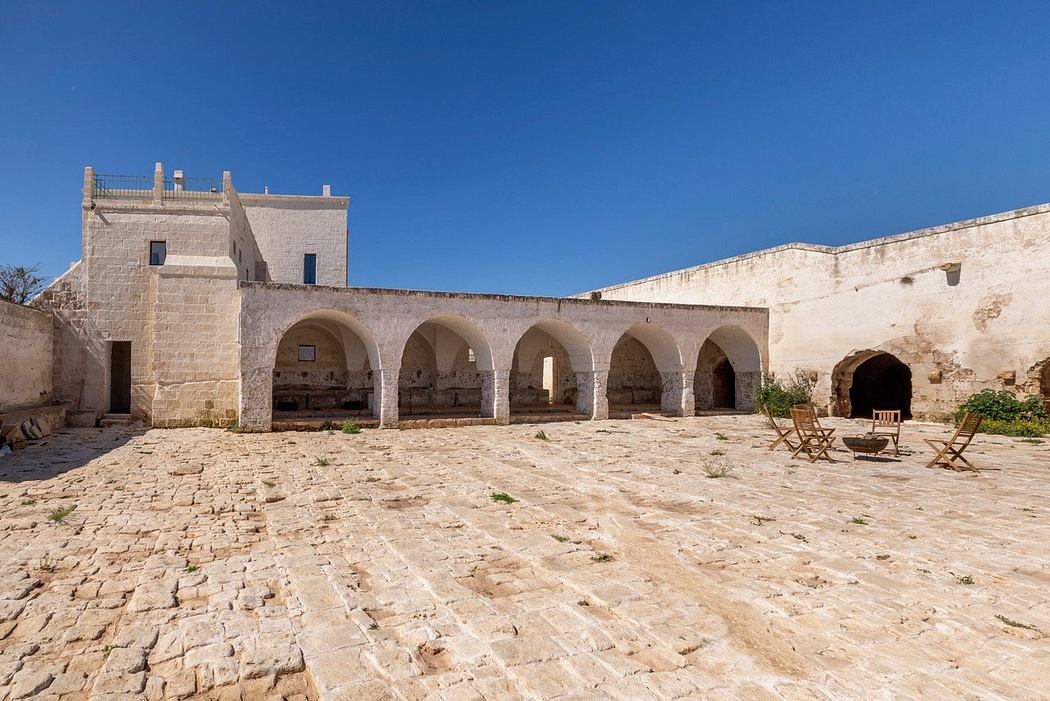 A historic stone building with arched entryways, open courtyard, and rustic furnishings.