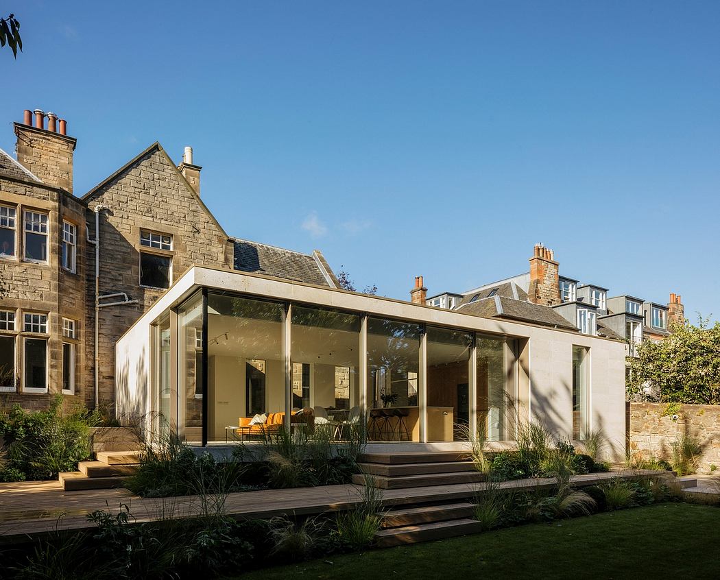Striking contemporary addition to a stone building, with floor-to-ceiling windows and a landscaped garden.