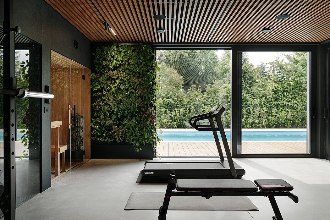 Sleek modern gym with lush green wall, expansive windows, and pool view.