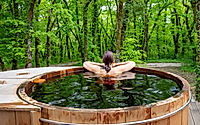 Woman in nordic bath in front of a forest.