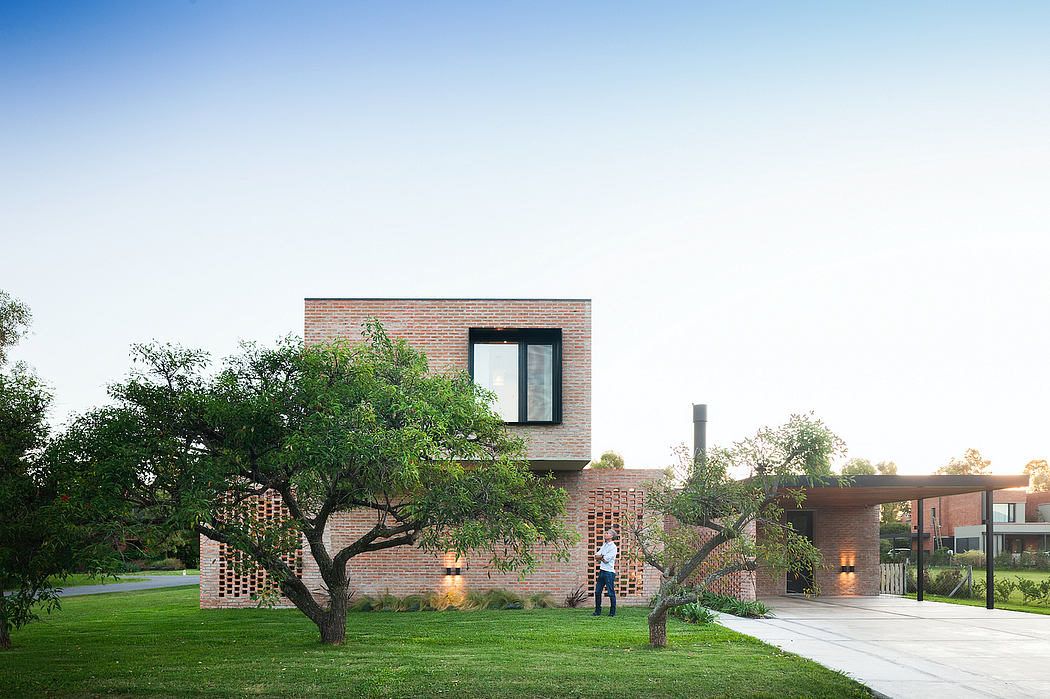 Modern brick building with large windows surrounded by lush greenery and landscaping.