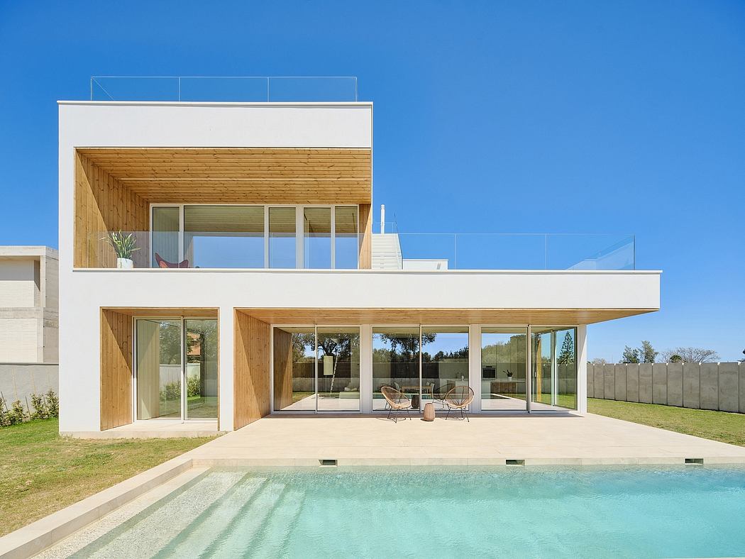 Contemporary glass and wood architecture with pool in foreground.
