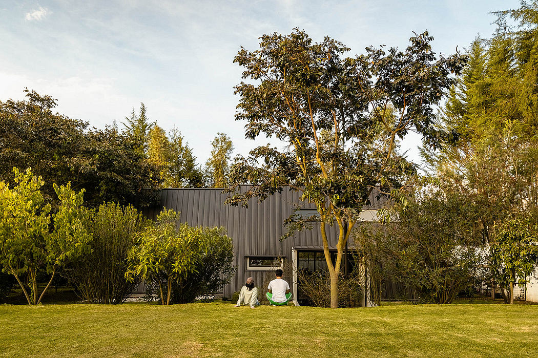 A modern, minimalist exterior with a dark metal facade, surrounded by lush greenery.