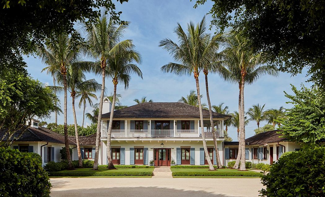 A grand, colonial-style villa surrounded by lush palm trees and a meticulously landscaped courtyard.