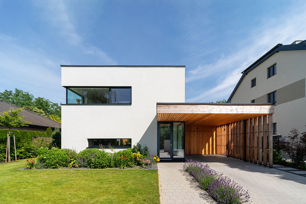 Modern white home with wooden accents, landscaped garden, and paved driveway.