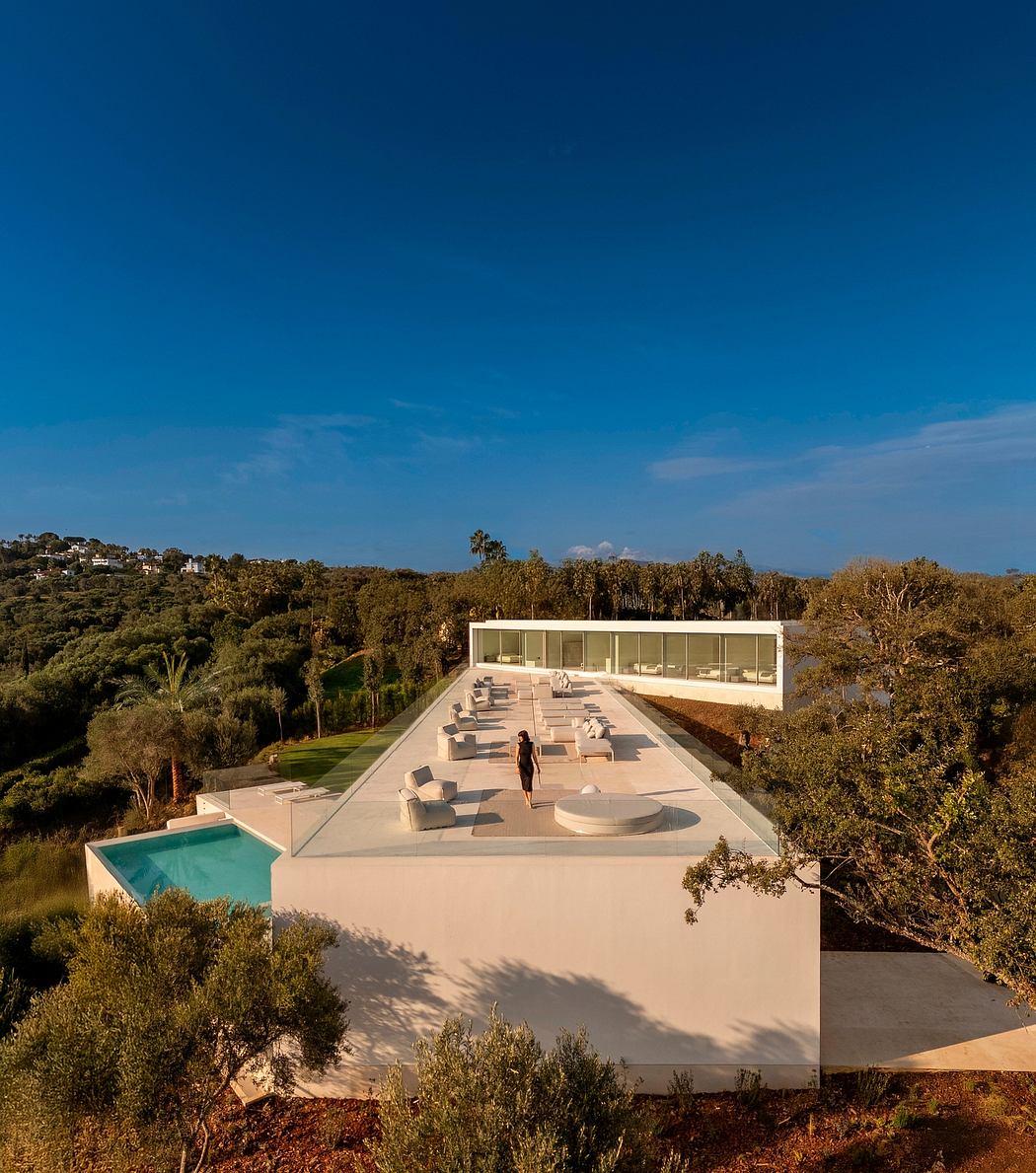 Sleek, modern villa with minimalist exterior and expansive deck overlooking lush landscape.