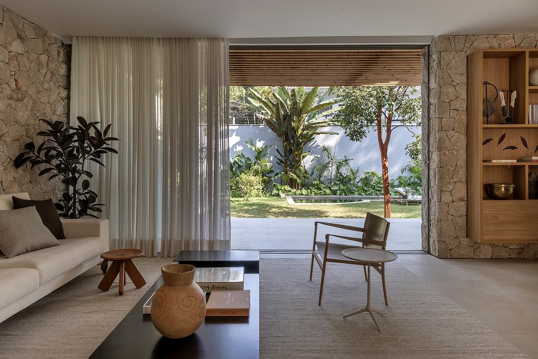 Minimalist living room with stone walls, large windows, and garden view. Wooden furnishings.