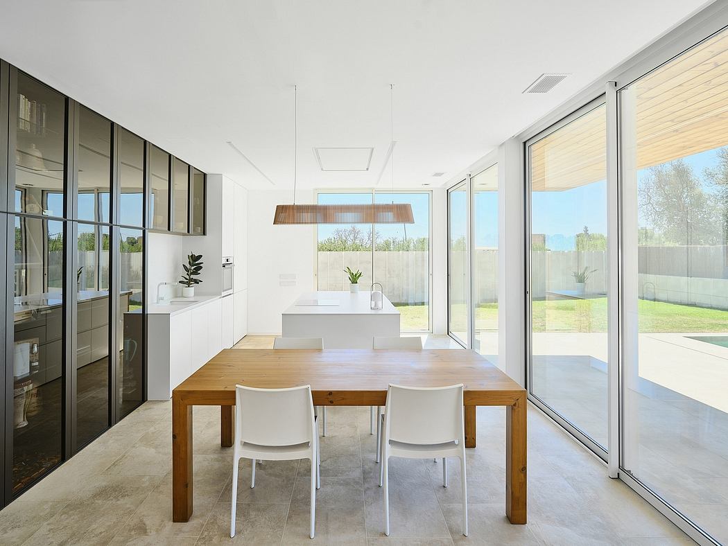 Minimalist dining room with large glass windows, modern lighting fixture, and sleek furniture.