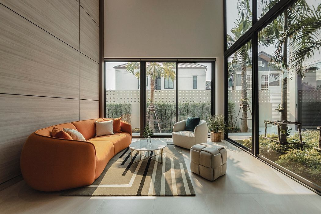 Modern living room with orange sofa, plush seating, and large windows overlooking lush greenery.