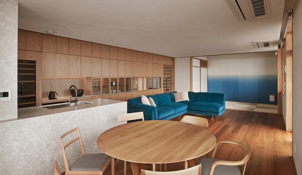 A modern, open-concept living space with sleek wood paneling, a blue sectional, and a round dining table.