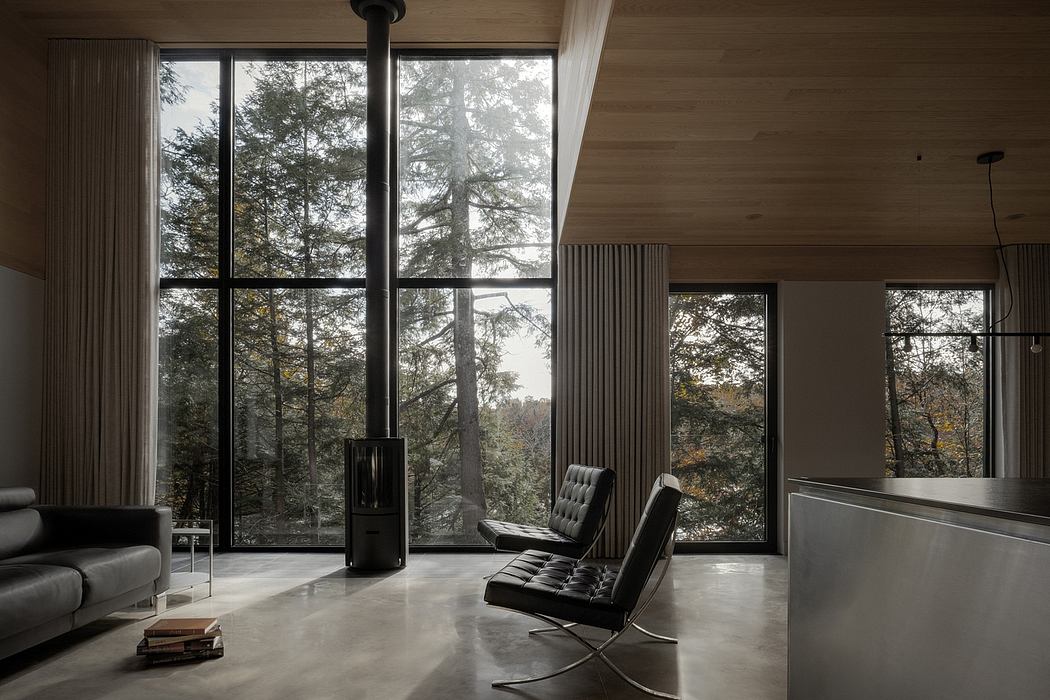 Minimalist interior with expansive floor-to-ceiling windows overlooking a forested landscape.