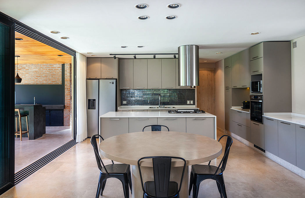 Sleek modern kitchen with wood accents, island seating, and industrial-style lighting.