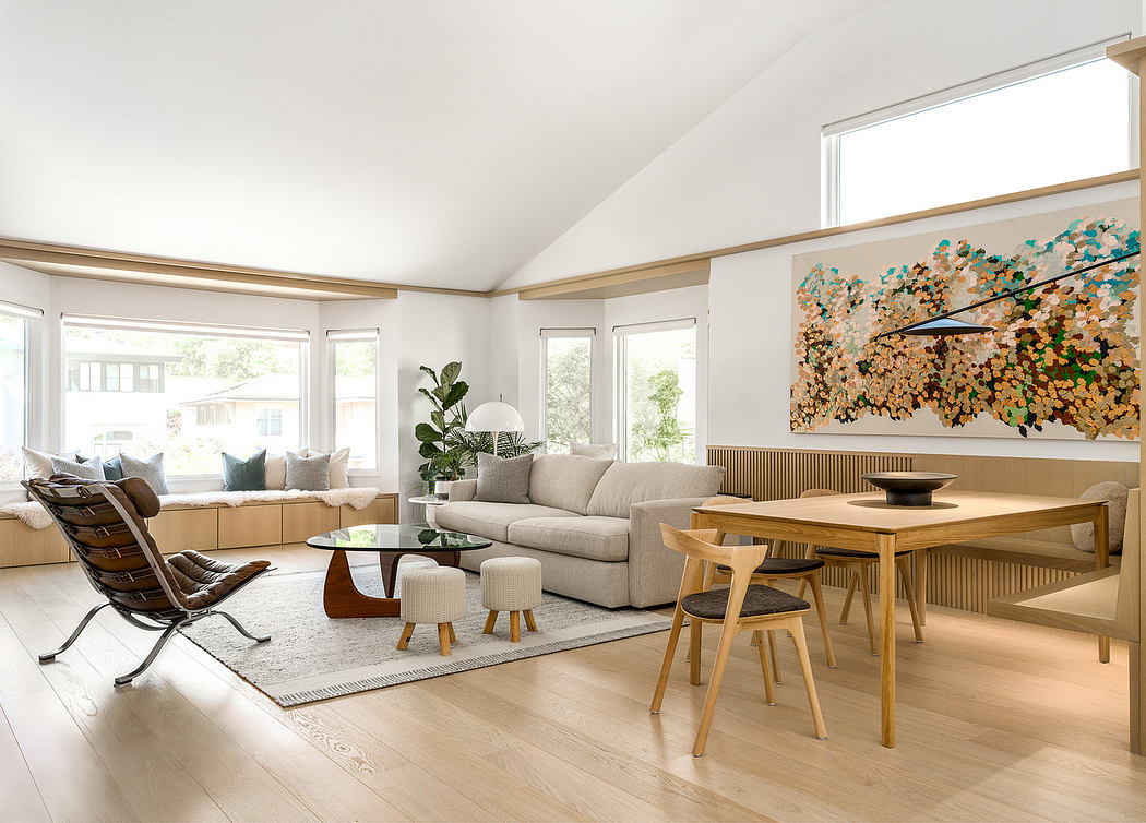 Large, open-concept living and dining area with floor-to-ceiling windows, wood paneling, and vibrant abstract artwork.