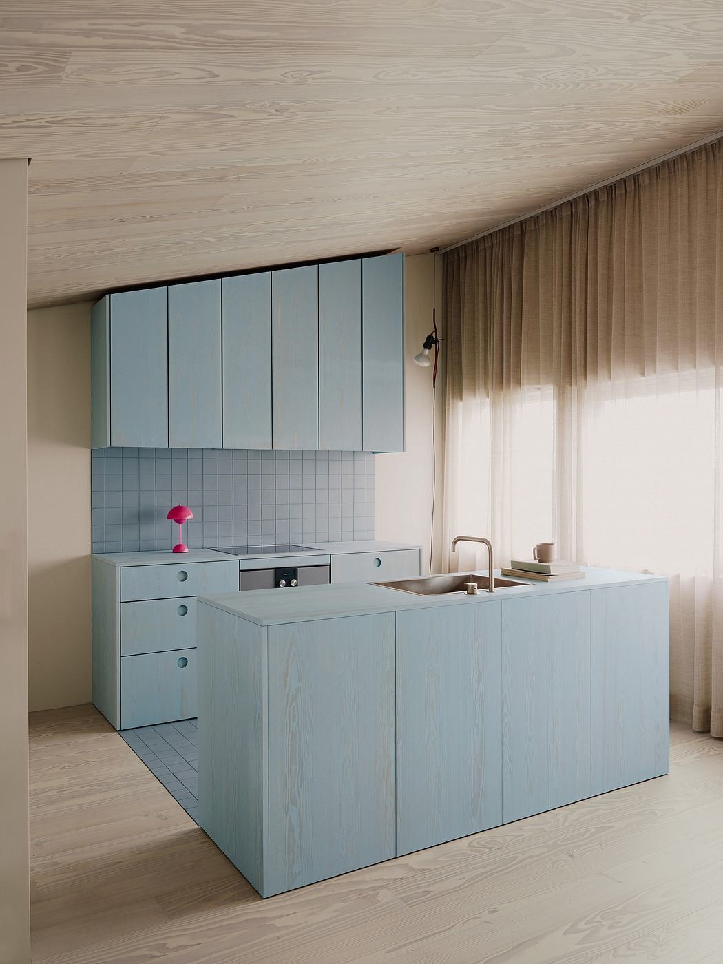 A modern, minimalist kitchen with clean lines, pale blue cabinets, and natural wood floors.