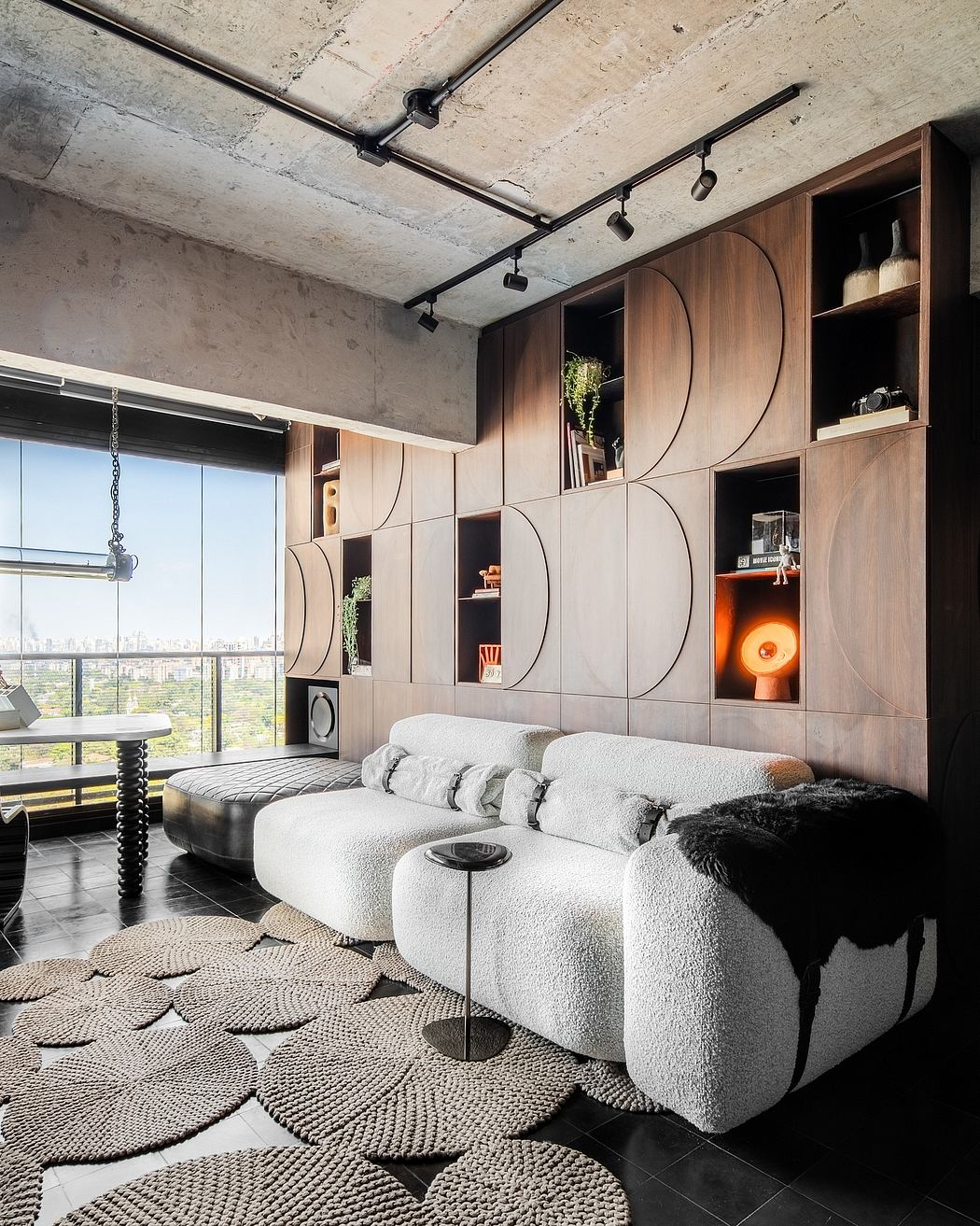 Modern loft-style interior with textured walls, built-in wood shelving, and a plush seating area.