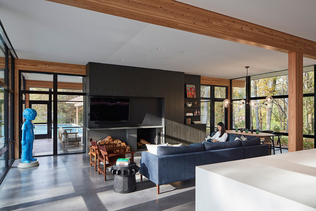 A modern living room with a wood-beamed ceiling, large windows, and a cozy gray sofa.