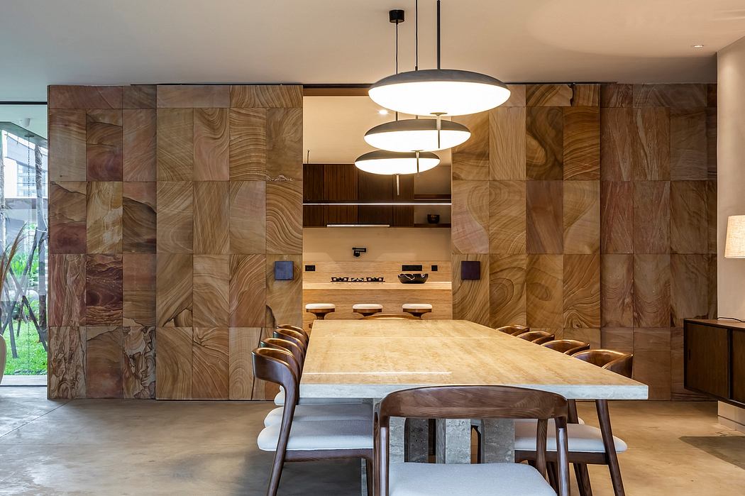 Spacious dining room with patterned wood panels, large wooden table, and modern pendant lights.