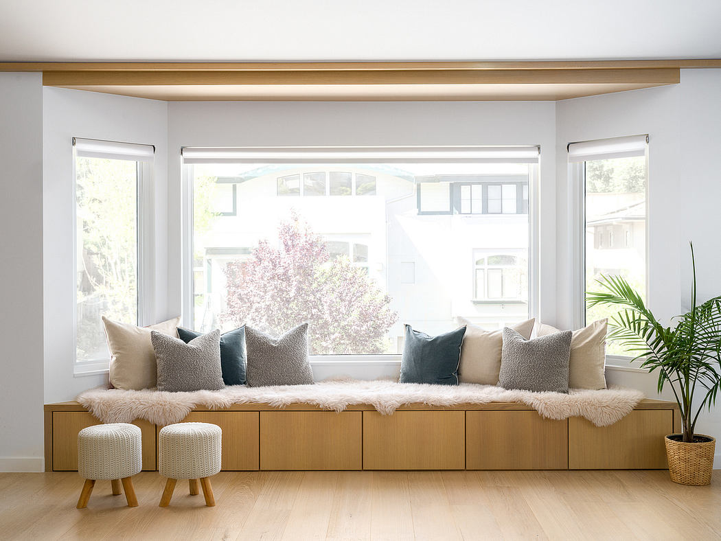 A modern, light-filled living space with a built-in window bench, neutral decor, and natural accents.