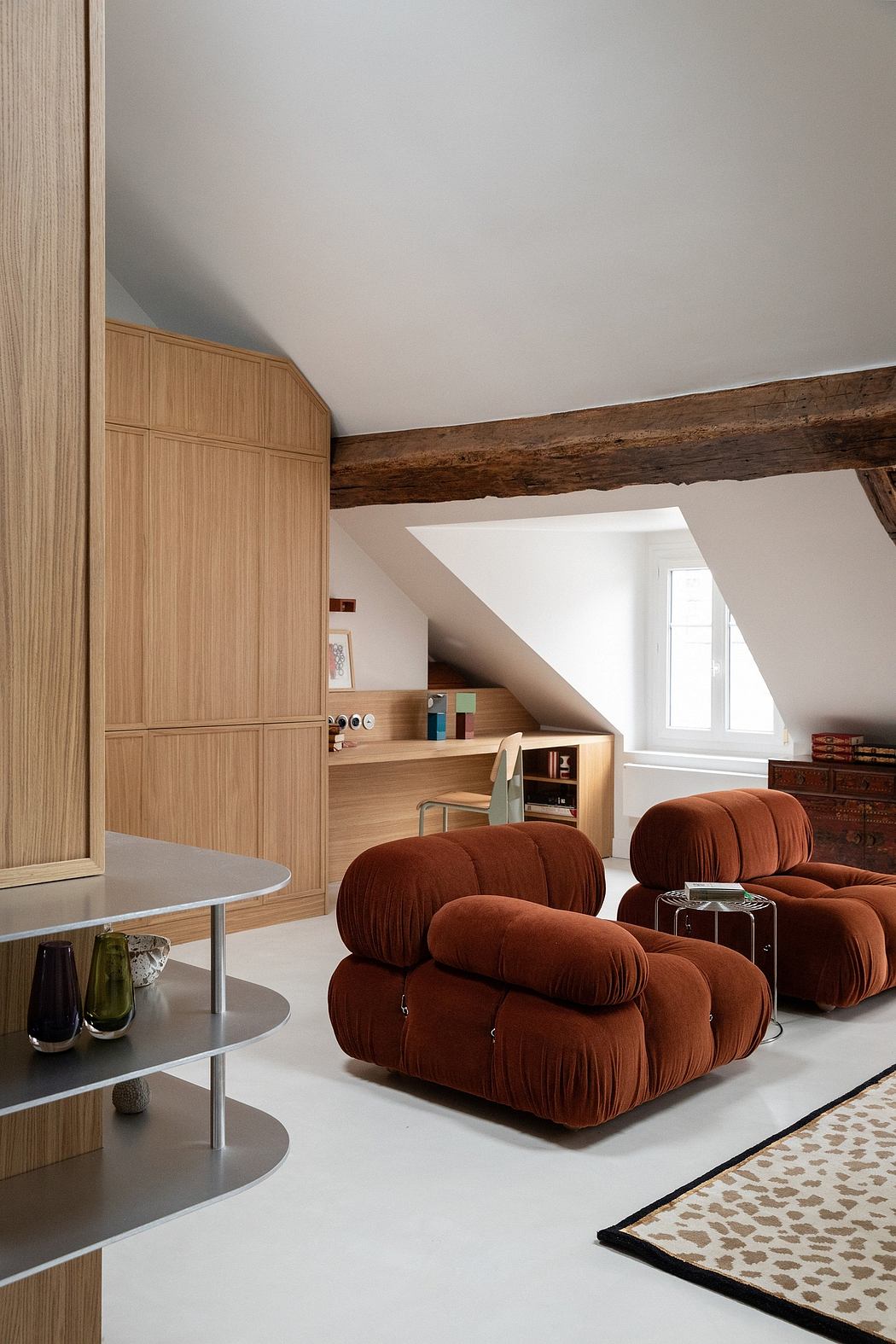 Cozy living space with wooden beams, built-in storage, and plush rust-colored seating.