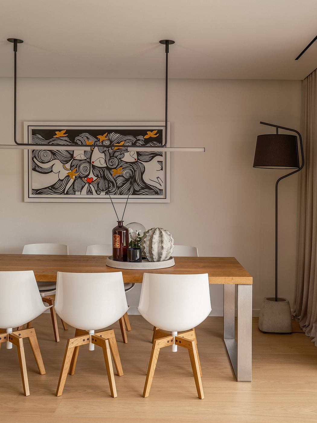 Modern dining area with abstract artwork, wood table, and white chairs with natural wood legs.
