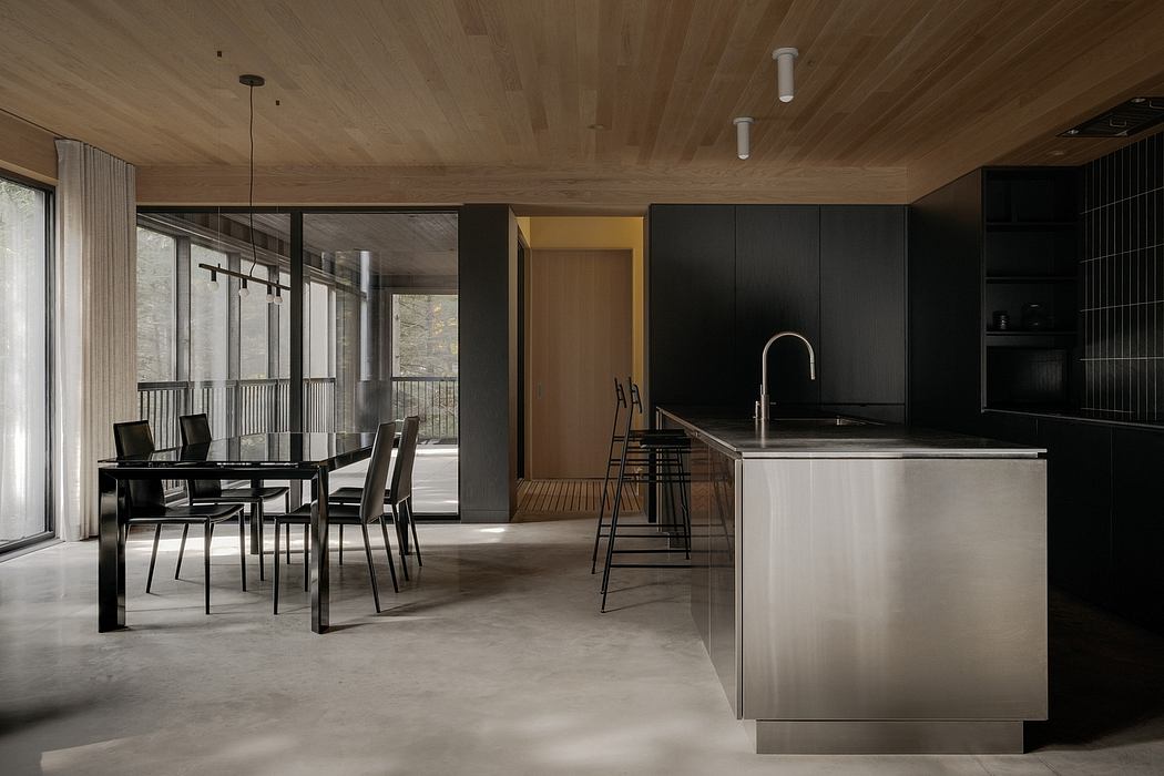 A modern, open-concept kitchen and dining area with sleek, dark cabinetry and a minimalist aesthetic.