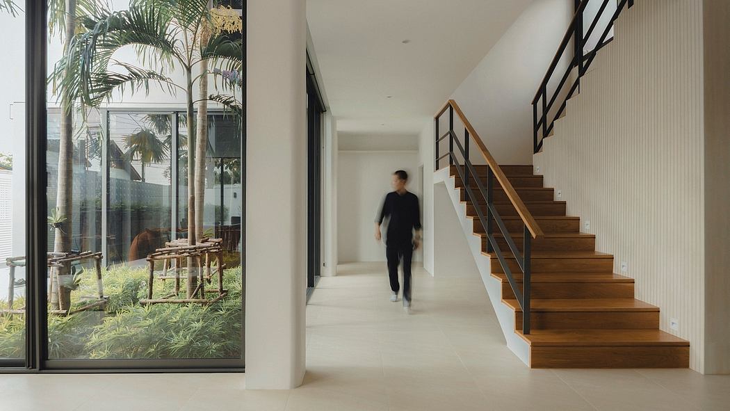 A modern, open-concept home with wooden stairs, glass walls, and lush indoor greenery.
