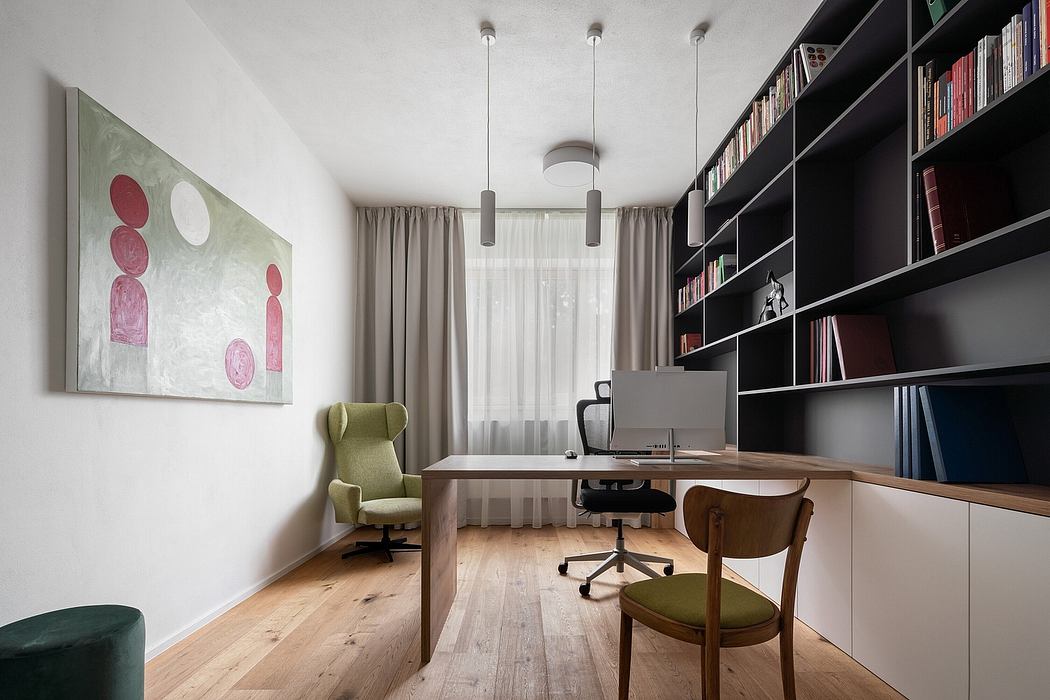 Cozy home office with wooden desk, bookshelves, green armchair, and abstract art.