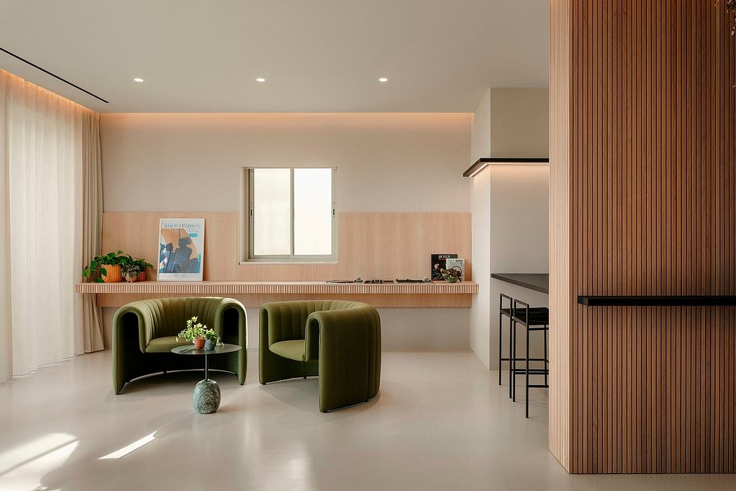 A modern, minimalist living space with sleek wooden accents, plush green chairs, and recessed lighting.