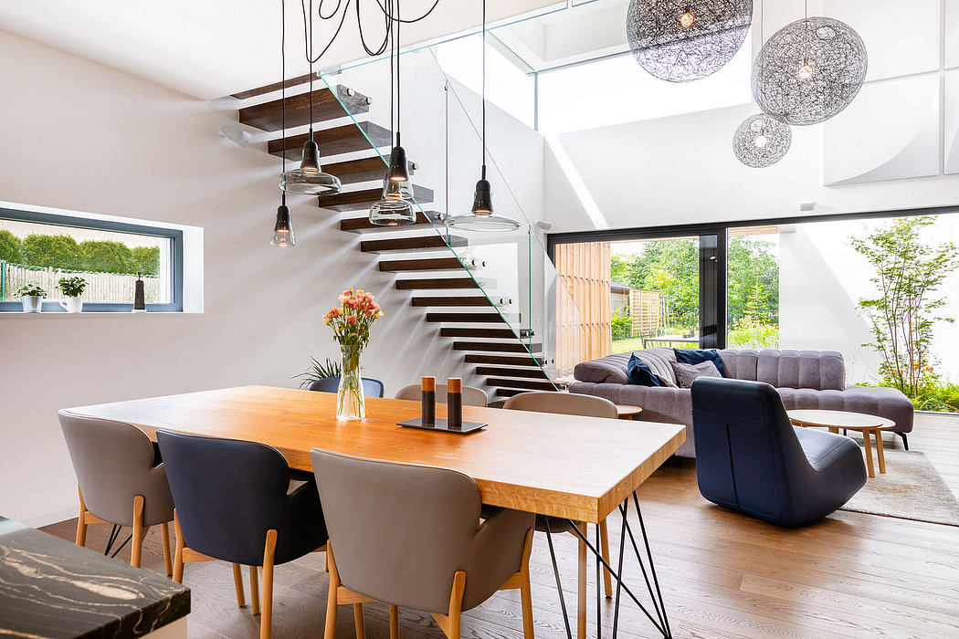 Spacious modern living area with open-plan design, wood-and-glass staircase, and statement lighting.
