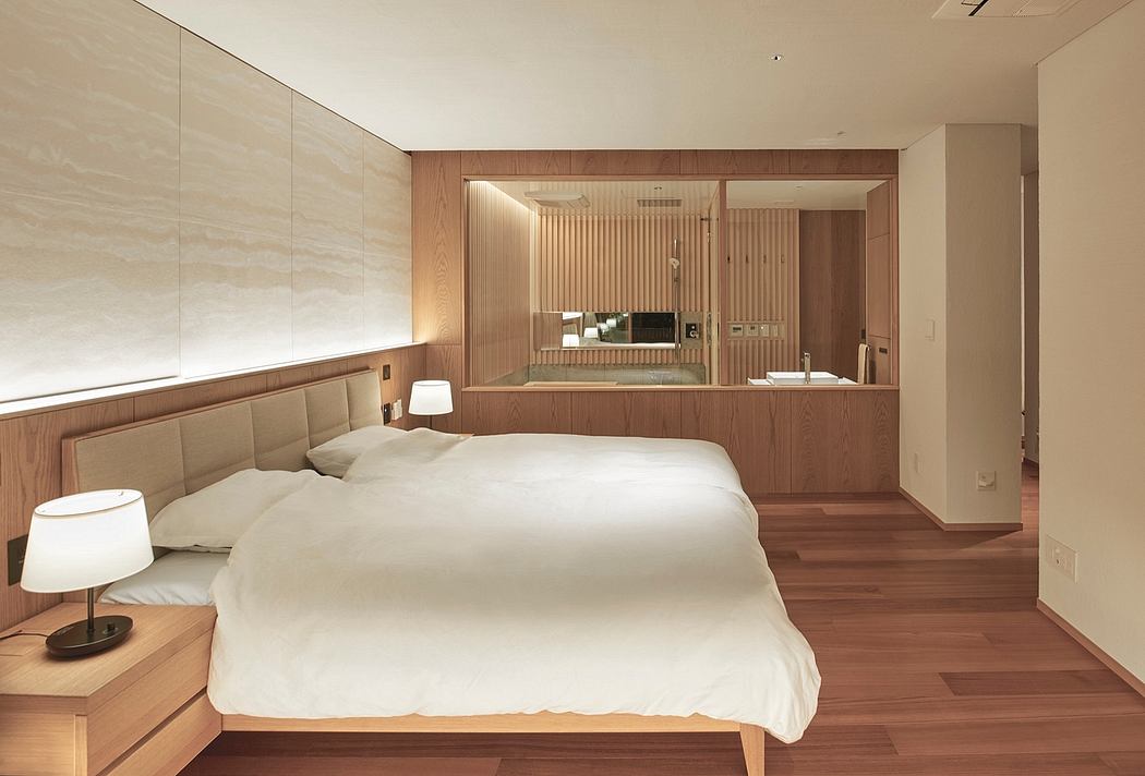 Spacious, modern bedroom with wood paneling, minimalist furniture, and integrated bathroom.