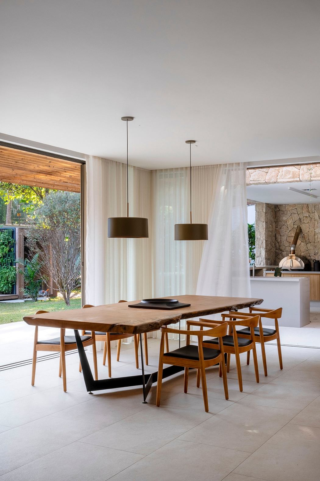Spacious dining area with wooden table, chairs, and pendant lights in modern interior.