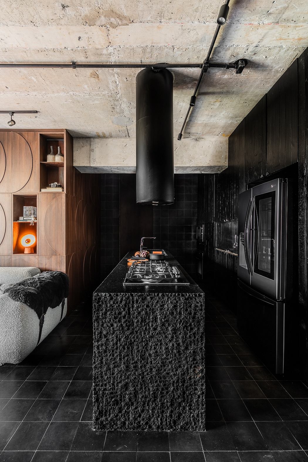 Moody, industrial-inspired kitchen with exposed concrete, black tiles, and a unique countertop design.
