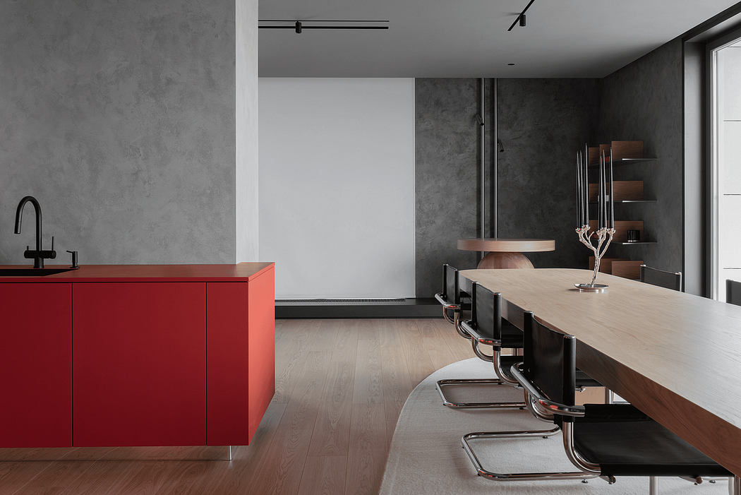 Modern kitchen with sleek red cabinets, wooden dining table, and gray concrete walls.