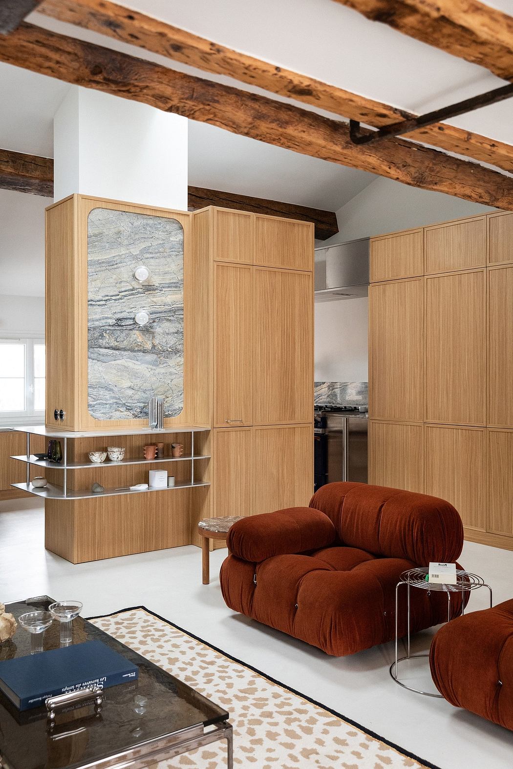 A cozy room with rustic wood beams, modern minimalist furniture, and a plush red sofa.