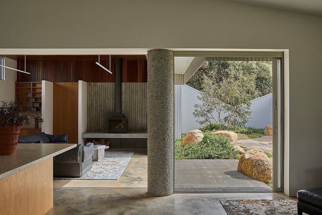A modern living room with wood paneling, fireplace, and large windows overlooking a natural landscape.