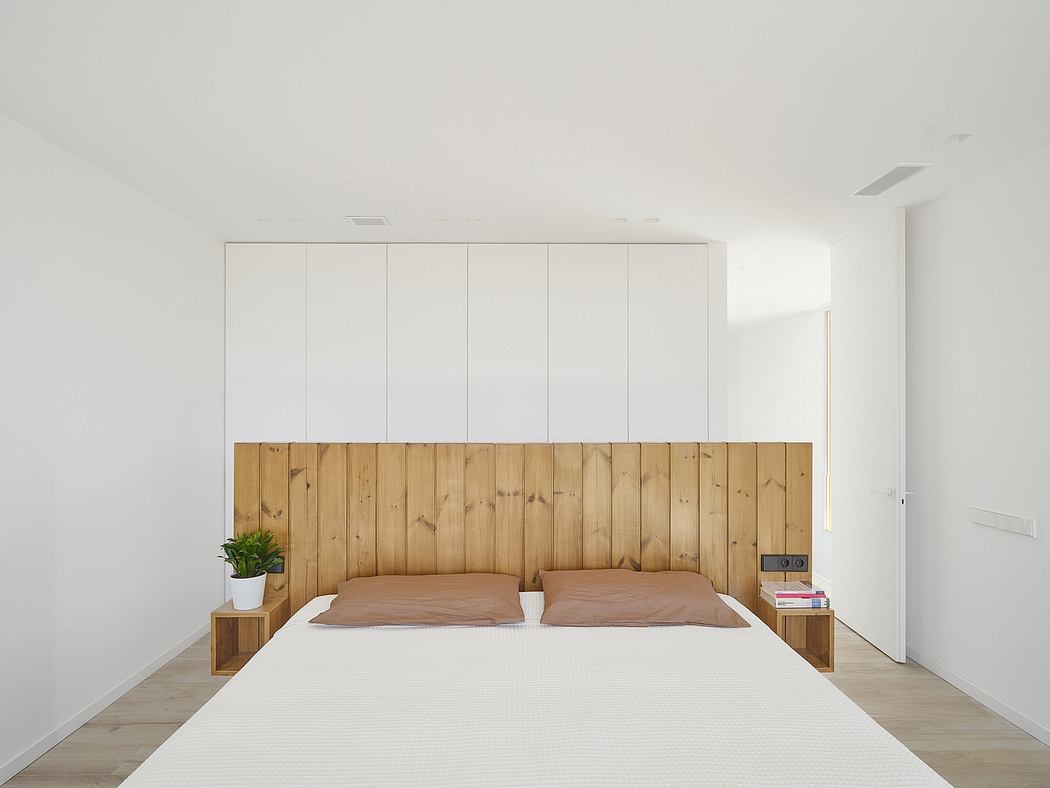 Minimalist bedroom with wooden accent wall, neutral color palette, and sleek built-in storage.