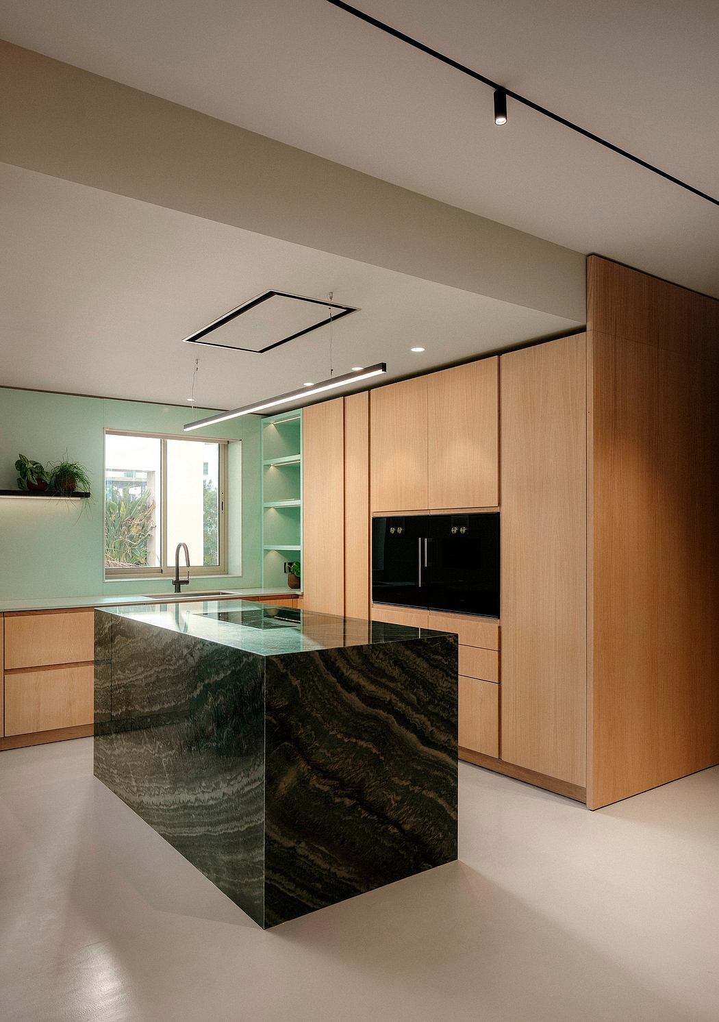 Sleek modern kitchen features dark stone countertop, wood cabinetry, and minimalist lighting.