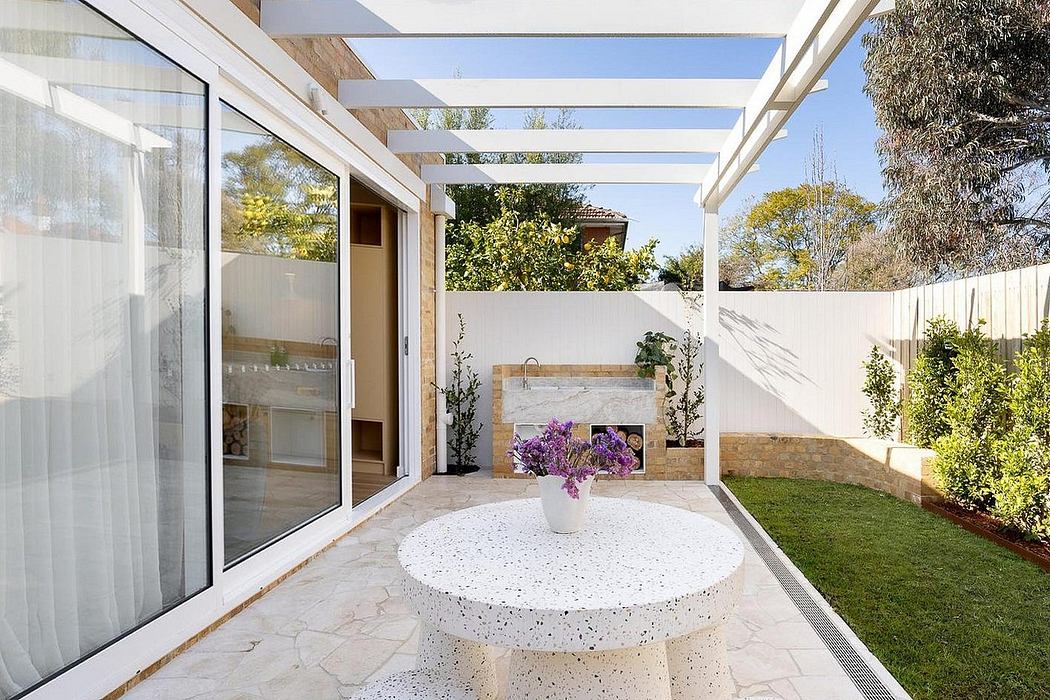 Modern patio with sleek pergola, terrazzo table, and lush greenery creating a serene outdoor space.