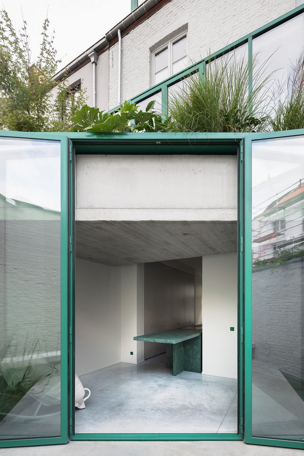A modern, minimalist architectural design featuring a glass-enclosed entrance with a built-in bench.