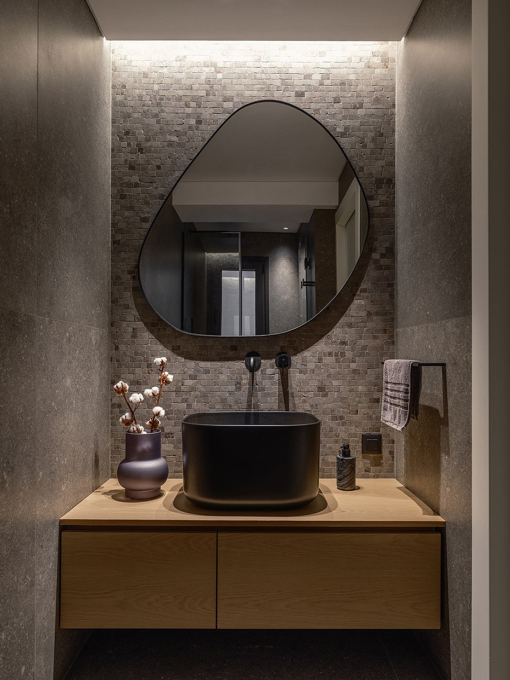 Sleek, modern bathroom design featuring a circular mirror, black vessel sink, and textured tile wall.